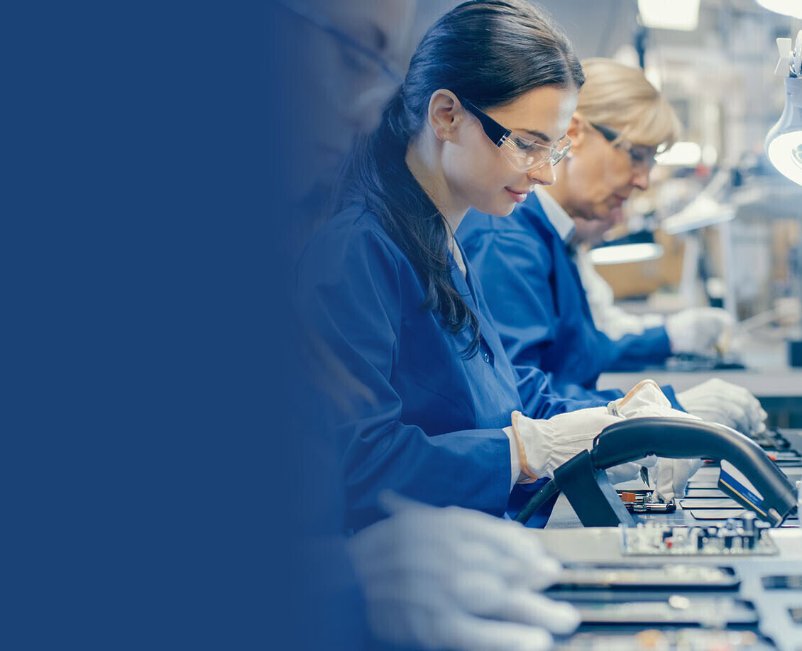 Female Electronics Factory Workers in Blue Work Coat and Protective Glasses Assembling Printed Circuit Boards for Smartphones with Tweezers. High Tech Factory with Employees.