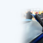 Close-up of a hand holding a smartphone displaying an NVB debit card on screen, with another physical NVB debit card partially visible, set against a branded background promoting Swipe to Save.