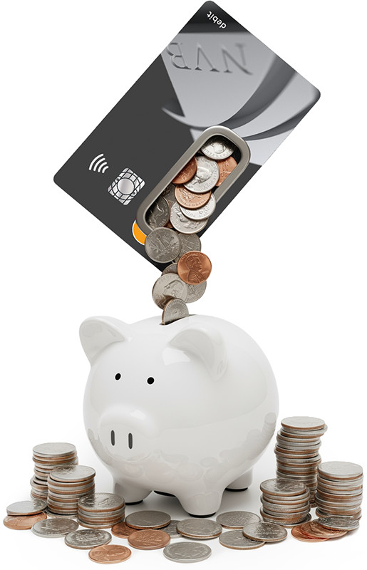 A debit card tilted above a white piggy bank with coins falling from the card’s chip area into the piggy bank, surrounded by stacks of coins.