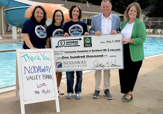 Andrew County Aquatics Initiative members and Nodaway Valley Bank representatives stand beside Savannah’s municipal pool holding a $100,000 Member Impact Fund donation check for the pool renovation project.